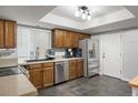 Well-equipped kitchen featuring stainless steel appliances, wooden cabinets, and dark tile flooring at 4028 S Atchison Way, Aurora, CO 80014