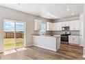 Bright kitchen featuring white cabinets, stainless steel appliances, and wood-look flooring at 48299 Shetland Dr, Bennett, CO 80102