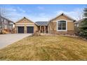 Inviting single-story home featuring a manicured lawn, a two-car garage, and stone accents adding to its curb appeal at 5118 Bottlebrush Run, Broomfield, CO 80023