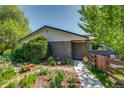Front yard featuring garden, lawn, and walkway leading to the gray brick ranch-style home at 3010 Zinnia Ct, Golden, CO 80401