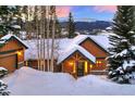 Mountain home with snowy roof and warm lighting at dusk at 699 Highlands Dr, Breckenridge, CO 80424