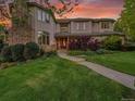 Elegant two-story home with landscaped yard, stone chimney, and a beautiful entrance enhanced by the sunset at 291 Fairchild Dr, Highlands Ranch, CO 80126