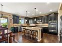 Open kitchen featuring dark cabinets, granite countertops, and a large island with seating at 22268 E Hidden Trail Dr, Parker, CO 80138