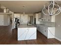 Bright, modern kitchen with white cabinets, marble countertops, stainless steel appliances, and decorative lighting at 13350 Imboden Rd, Hudson, CO 80642