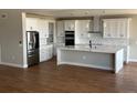 Spacious kitchen featuring white cabinetry, stainless steel appliances, large marble island, and hardwood flooring at 13350 Imboden Rd, Hudson, CO 80642