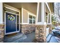 Inviting front entrance with a blue door, stone accents, and a porch at 5808 S Duquesne Ct, Aurora, CO 80016