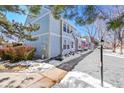 The exterior of a light blue townhome featuring fresh landscaping and a shoveled sidewalk in a snow-covered area at 7918 S Depew St # D, Littleton, CO 80128