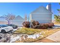 Townhome exterior with a two-car garage, landscaped bushes, and two cars parked on the driveway at 7918 S Depew St # D, Littleton, CO 80128