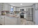 Bright kitchen featuring white cabinets, stainless steel appliances, and modern countertops at 4713 S Robb St, Littleton, CO 80127
