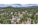 Expansive aerial view of a neighborhood nestled among lush trees and rolling hills, offering a serene setting at 31190 Cinnamonwood, Evergreen, CO 80439