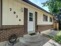 A well maintained front entrance and porch featuring a brick facade, white painted siding, and concrete steps at 7936 Eaton St, Arvada, CO 80003