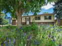 Charming single-story home featuring a brick facade, attached garage, and mature landscaping with bright colored flowers at 7936 Eaton St, Arvada, CO 80003