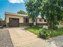Charming single-story home featuring a brick facade, attached garage, and long concrete driveway at 7936 Eaton St, Arvada, CO 80003