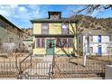 Quaint two-story house with a distinctive yellow facade and a decorative iron fence at 1918 Virginia St, Idaho Springs, CO 80452