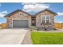Stone and siding home features a gray garage door and a well-maintained lawn, creating an inviting curb appeal at 6384 E 154Th Pl, Thornton, CO 80602