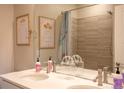 Bathroom features a double vanity, large mirror, neutral paint, and shower with tile surround at 10018 E 62Nd Ave, Denver, CO 80238
