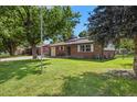 Traditional home with a well-manicured lawn, mature trees, and a brick facade at 5193 Zinnia St, Arvada, CO 80002