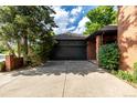 Attached two-car garage with a neutral color door, concrete driveway, and brick facade details at 5401 E Dakota Ave # 22, Denver, CO 80246