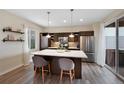 Modern kitchen featuring a large island with seating, sleek cabinets, stainless steel appliances, and wood floors at 9624 Dunning Cir, Highlands Ranch, CO 80126