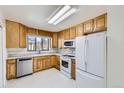 Clean kitchen with light wood cabinets, stainless dishwasher, and white appliances with white tile floors at 2070 Kingston St, Aurora, CO 80010