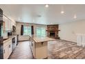 Open floor plan showcasing the kitchen island leading to a stone fireplace at 679 S Pearl St, Elizabeth, CO 80107