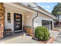 Charming front entrance with a modern door, stone accents, lush greenery, and a cozy bench at 2999 Olympia Cir, Evergreen, CO 80439