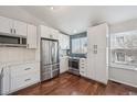 White kitchen boasts stainless steel appliances, sleek cabinetry, herringbone backsplash, and hardwood floors at 11072 Quail Ct, Parker, CO 80134