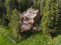 Aerial shot showing the house with a spacious deck and fenced yard, surrounded by lush greenery at 10858 Norton Ave, Conifer, CO 80433