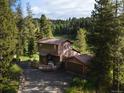 Exterior view of a charming two-story home with a deck and a detached garage nestled among trees at 10858 Norton Ave, Conifer, CO 80433