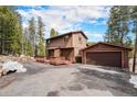 Inviting two-story home with a charming front porch and a detached garage in a wooded setting at 10858 Norton Ave, Conifer, CO 80433