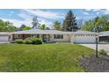 Landscaped front yard showcases mature trees and lush green grass surrounding a single-story residence with an attached garage at 11328 W 27Th Ave, Lakewood, CO 80215
