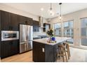 Modern kitchen with stainless steel appliances, dark cabinets, and a large island at 2695 W Grand Ave, Littleton, CO 80123