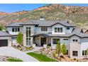 Elegant home exterior with a three-car garage and stone accents, complemented by mature landscaping at 15191 Dinosaur Ridge Rd, Morrison, CO 80465