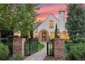 Charming Tudor-style home with stone walkway, manicured lawn, and mature landscaping at dusk at 5530 E 6Th Ave Pkwy, Denver, CO 80220