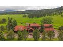 Charming exterior elevation of a wood-sided home with a red roof, lush trees, and a well-maintained front yard at 5939 Lone Peak Dr, Evergreen, CO 80439