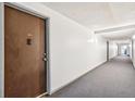 Well-lit hallway with gray carpet leading to unit 104 at 10211 Ura Ln # 3-104, Thornton, CO 80260
