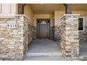 Close up of a covered front porch with stone columns, wood trim, and a stylish front door at 9510 Orion Way, Arvada, CO 80007
