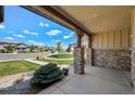 Covered front porch view featuring stone columns, well-manicured landscaping and neighborhood street at 9510 Orion Way, Arvada, CO 80007