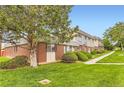 Exterior view of townhomes showing well-maintained lawns, mature landscaping, and brick accents at 8613 Santa Fe Dr, Thornton, CO 80260