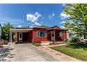 Red bungalow featuring a cozy porch and convenient covered carport, nestled under a bright sky at 753 S Utica St, Denver, CO 80219