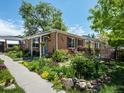 Charming brick home showcasing a well-manicured front garden with colorful flowers and stepping stones at 3580 Krameria St, Denver, CO 80207