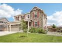 Attractive home with stone facade, red shutters, green lawn, and tidy landscaping at 16881 E 110Th Ave, Commerce City, CO 80022