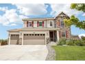 Lovely two-story home features a three-car garage, stone accents, and a charming front porch at 16881 E 110Th Ave, Commerce City, CO 80022