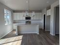 Modern kitchen with white cabinets, stainless steel appliances, an island, and hardwood floors at 16815 Mckay Dr, Mead, CO 80542