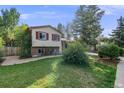 Charming home with a well-manicured lawn, mature trees, and a welcoming facade on a sunny day at 8952 W Stanford Ave, Denver, CO 80123