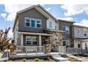 Stylish townhome showcasing a covered front porch with stone pillars and gray siding at 1500 Sun Way, Lafayette, CO 80026