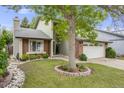 Charming two-story home featuring a well-manicured lawn, mature tree, and a brick and stone facade at 3889 S Fraser St, Aurora, CO 80014