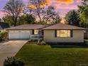 Charming single-story home with a manicured lawn, inviting front porch, and a two-car garage under a colorful evening sky at 6943 Oak Way, Arvada, CO 80004