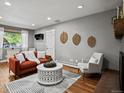 Cozy living room featuring hardwood floors, an orange sofa, accent chair, and decorative wall art at 6943 Oak Way, Arvada, CO 80004