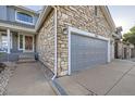 Close-up view of the three-car garage with stone accents and a paved driveway at 8915 S Field Ct, Littleton, CO 80128